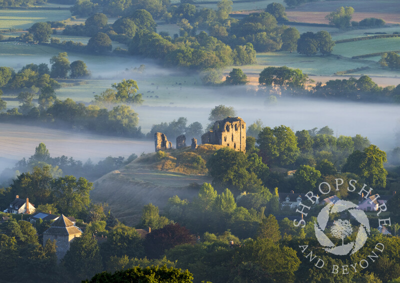 Sunlight picks out Clun Castle rising above the early morning mist, Shropshire.